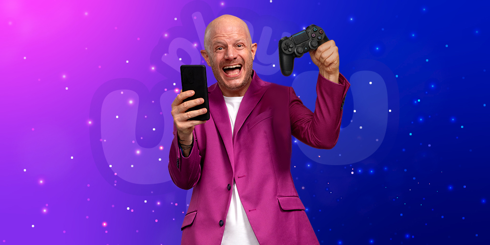 FACUNDO VIENDO DE FRENTE Y QUE EN LA MANO TENGA TANTO SU TELÉFONO COMO EN LA OTRA MANO, QUE ESTÉ SOSTENIENDO UN MANDO GAMER COMO SI ESTUVIERA INVITANDO AL UZUARIO A ENTRAR A PLAYUZU